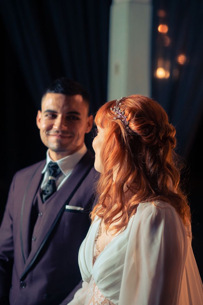 à propos A bride and groom smiling warmly during an intimate wedding ceremony indoors.